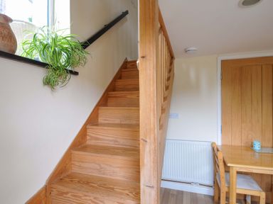 A dining area with stairs and table at Little Hamlin in Rilla Mill Nr Callington