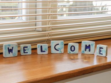 Decorative letters spelling welcome on a wooden windowsill with horizontal blinds at Honeysuckle Cottage in Helston