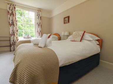 A bedroom with two beds each with a decorative pillow and rolled towels at Penwarne Lodge in Mawnan Smith