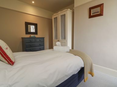A bedroom with bed and pillow blankets a wardrobe a chest of drawers and a mirror at Penwarne Lodge in Mawnan Smith