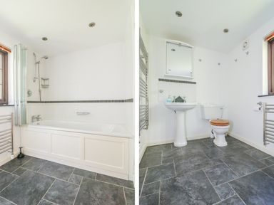 A bathroom with a bathtub shower and window and a bathroom with a sink toilet mirror and towel racks at Carne Mill in Manaccan