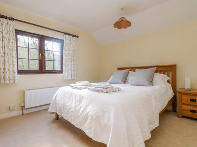 A bedroom with a bed with pillows and folded towels next to a window and a wooden bedside table at Carne Mill in Manaccan