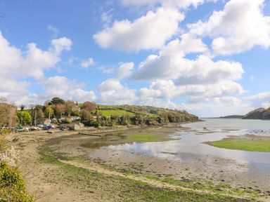 A coastal inlet with boats on shore and green hills in the background at Carne Mill in Manaccan