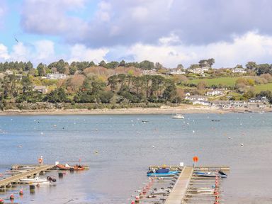 A harbor with docks and boats on the water with houses and trees on the shore at Carne Mill in Manaccan