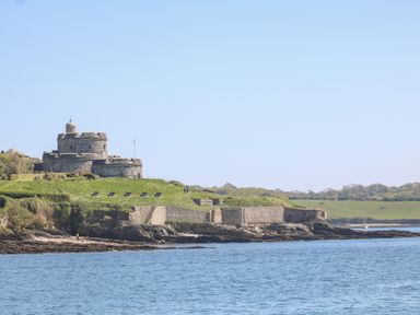 A stone fortress with cannons on a grassy coastline by the sea at Little Chycoose in Truro