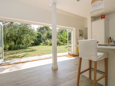 A kitchen with a high chair near an open door leading to a grassy garden at Little Chycoose in Truro