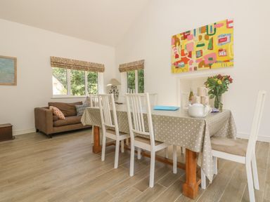 A dining room with table and chairs and a small sitting area with sofa by windows at Little Chycoose in Truro