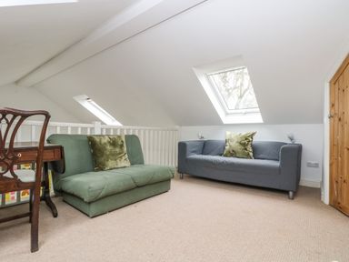 A small seating area with green and gray sofas under skylights with a wooden door and desk at Little Chycoose in Truro