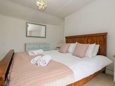 A bedroom with a wooden bed and a blue dresser with a mirror at Little Chycoose in Truro
