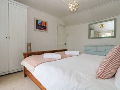 A bedroom with a wooden bed a blue chest of drawers and a white wardrobe at Little Chycoose in Truro