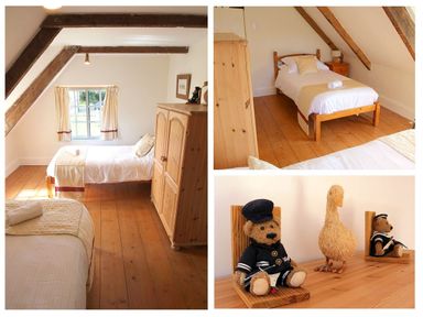 A bedroom with two single beds wooden furniture and stuffed toys on a wooden surface at Rose Cottage in Manaccan