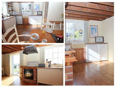 A kitchen with wooden floors white cabinets a table set for breakfast and a brick surround oven at Rose Cottage in Manaccan