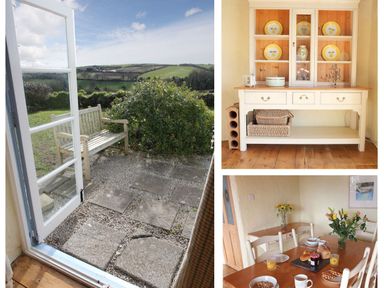 An open door leading to a garden bench and countryside view a white cabinet with yellow plates and wicker baskets a dining table set with breakfast items and flowers at Rose Cottage in Manaccan