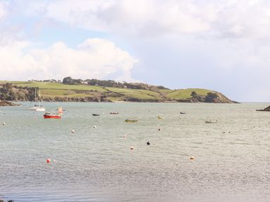 A coastal scene with boats on the water and green hills in the background at Banneth in Helford