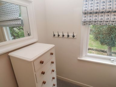 A bedroom with a chest of drawers and coat hooks at Banneth in Helford