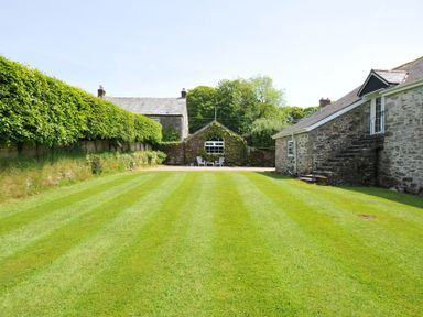 A garden with grass and buildings at Trevenning Chapel Near Port Isaac