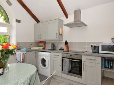 A kitchen with appliances and a dining table at Trevenning Chapel Near Port Isaac