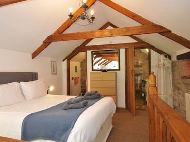 A bedroom with a bed and wooden furniture at Trevenning Chapel Near Port Isaac
