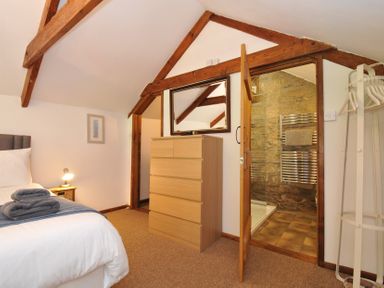 A bedroom with a dresser and a bathroom door at Trevenning Chapel near Port Isaac
