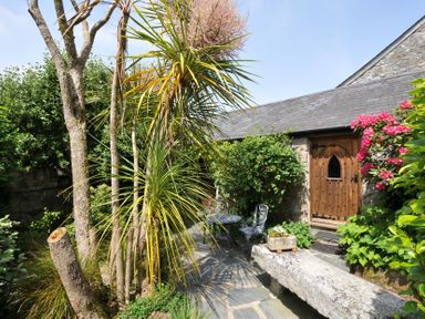 A garden with plants and a stone bench at Trevenning Chapel near Port Isaac