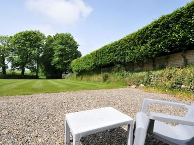 A garden with a gravel area and trees at Trevenning Chapel near Port Isaac