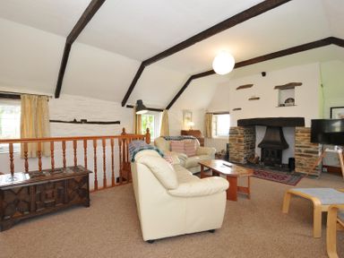 A living room with a fireplace and sofa at Trevenning Barn near Port Isaac