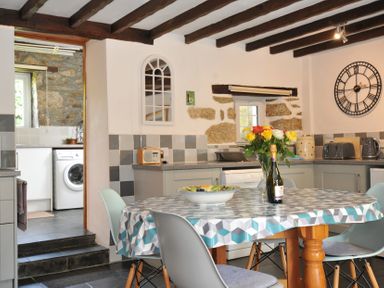 A kitchen with a table and flowers at Trevenning Barn Near Port Isaac