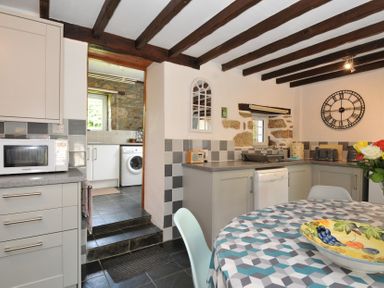 A kitchen with appliances and a table at Trevenning Barn Near Port Isaac