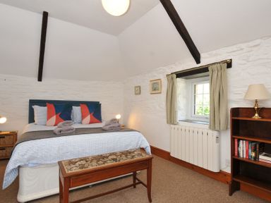 A bedroom with a bed and bookshelf at Trevenning Barn Near Port Isaac