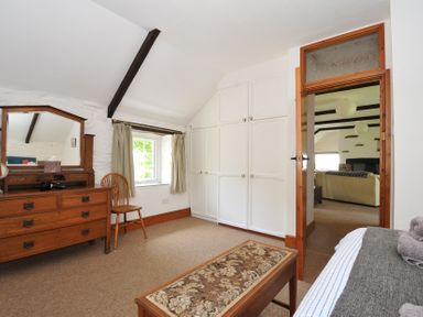 A bedroom with a dresser, mirror, and wardrobe at Trevenning Barn Near Port Isaac