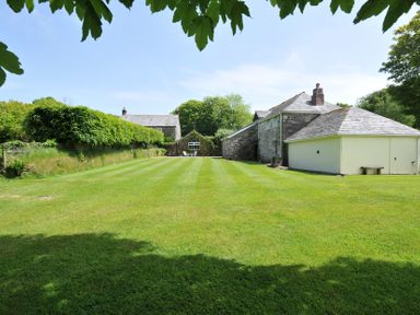A garden with grass and trees at Trevenning Barn near Port Isaac