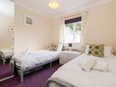 A bedroom with two single beds white bedding and leaf patterned cushions at Treacle in Falmouth