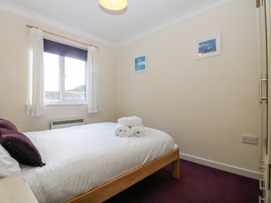 A bedroom with a bed and folded towels on it next to a window with curtains at Trelease in Falmouth