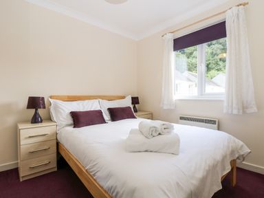 A bedroom with a double bed bedside tables and lamps next to a window at Trelease in Falmouth