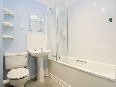A bathroom with a toilet pedestal sink and bathtub with shower at Trelease in Falmouth
