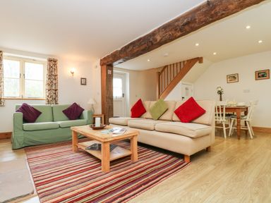 A living room with two sofas and a wooden coffee table on a striped rug at Apple Cottage in Colebrooke near Crediton