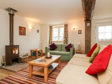 A living room with a wood-burning stove two sofas a coffee table and striped rug at Apple Cottage in Colebrooke near Crediton