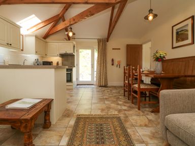 A kitchen with a dining area and wooden ceiling beams at Roosters in Lostwithiel