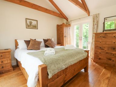 A bedroom with a wooden bed chest of drawers a wardrobe and a nightstand at Roosters in Lostwithiel