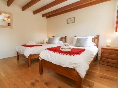 A bedroom with two single wooden beds bedside tables and lamps at Roosters Lostwithiel