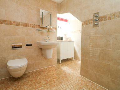 A bathroom with a wall mounted toilet sink and a white cabinet at Roosters in Lostwithiel