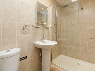 A bathroom with a toilet sink mirror and glass shower enclosure at Byre in Lostwithiel