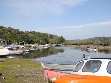 A river with moored boats and trees along the shore at Byre in Lostwithiel