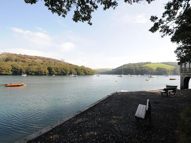 A river with boats and benches on the shore at Byre in Lostwithiel