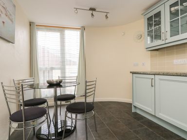 A kitchen dining area with a round glass table and four metal chairs near a window at Mynheer Farm Barn Nr Portreath