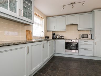 A kitchen with cabinets countertops a window sink coffee maker kettle toaster microwave and oven at Mynheer Farm Barn Nr Portreath