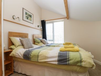 A bedroom with two single beds with striped bedding and yellow towels on top at Mynheer Farm Barn Nr Portreath