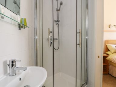 A bathroom with a shower enclosure and a sink next to a bedroom at Mynheer Farm Barn Nr Portreath