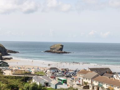 A beach with people and buildings near the shore at Mynheer Farm Barn Nr Portreath