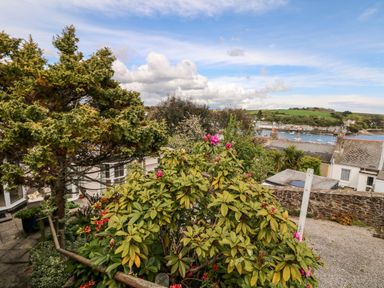 A garden with flowering bushes and trees overlooking a harbor with boats and houses at Seabien in Falmouth